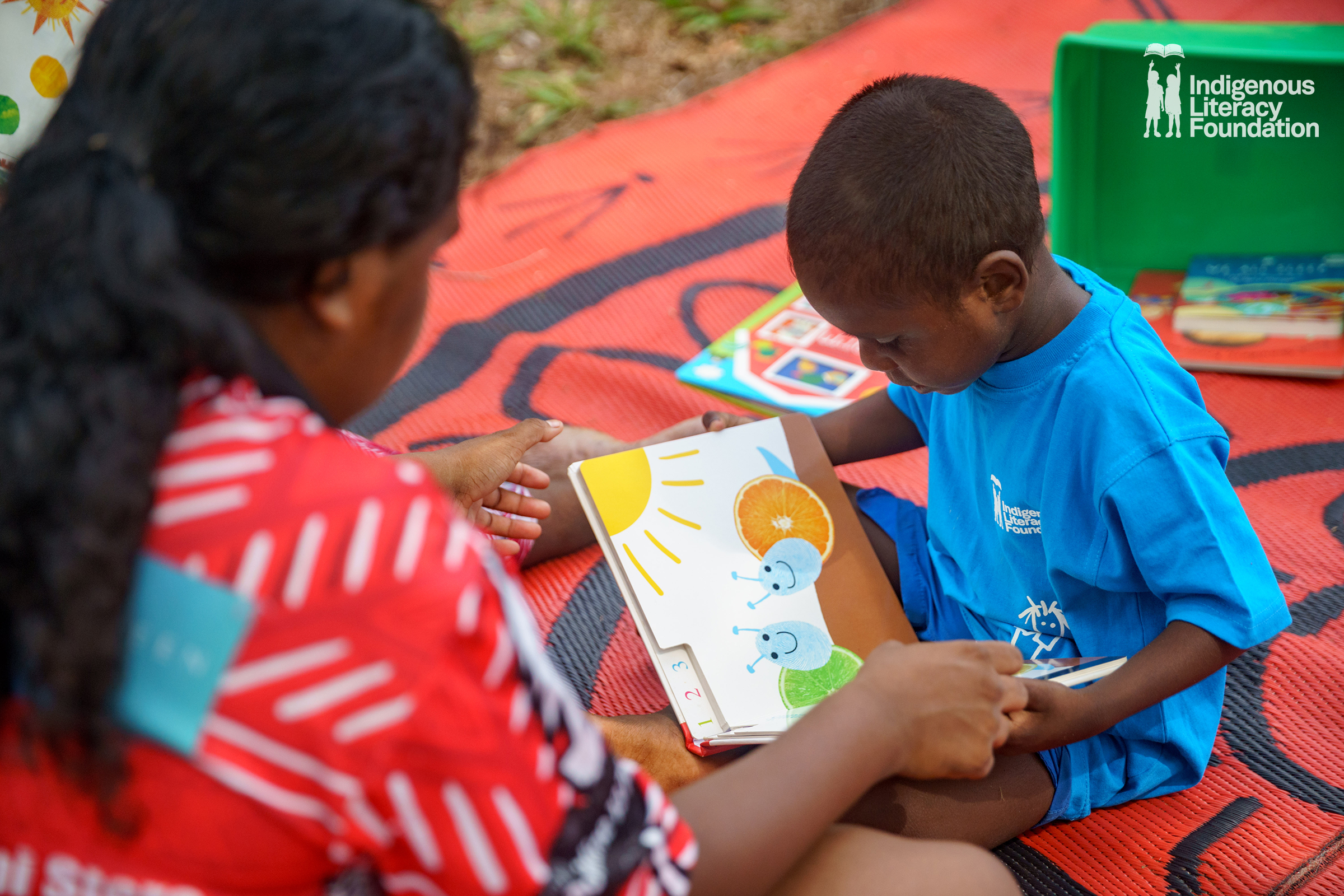 A woman and child sit reading a picture book.