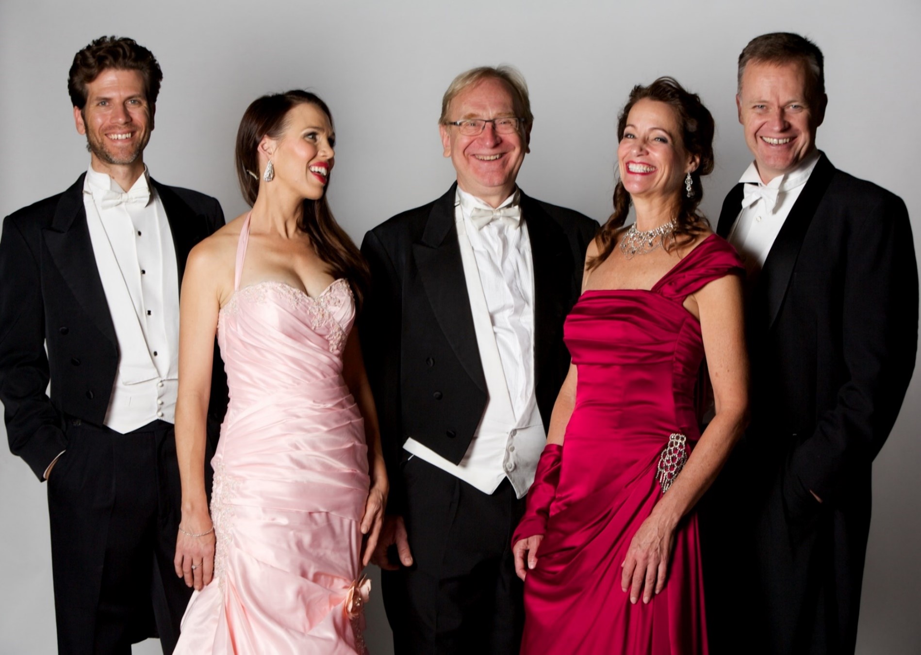 Five people dressed in formal attire smiling and laughing