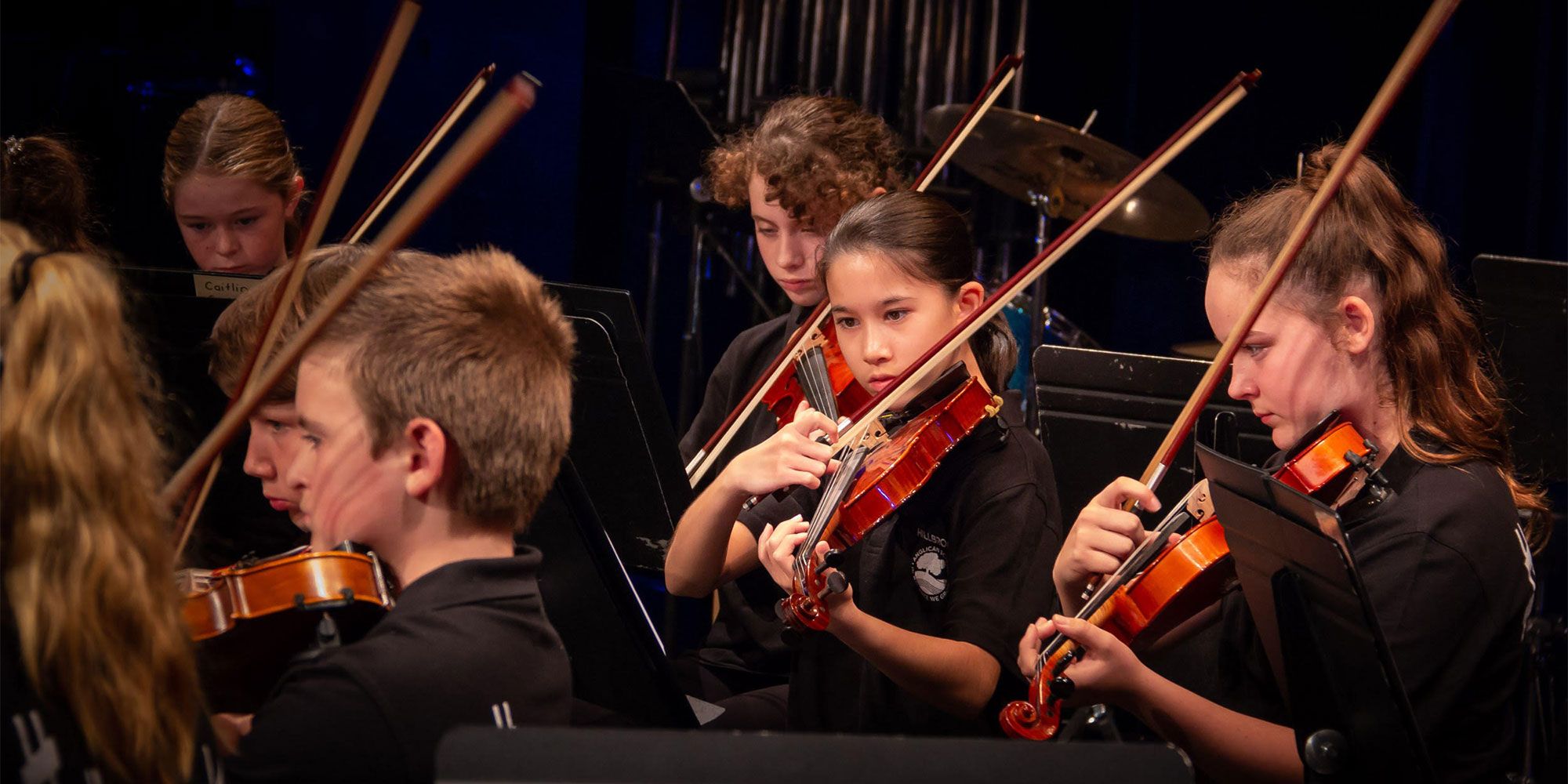 Young children playing string instruments in an orchestra