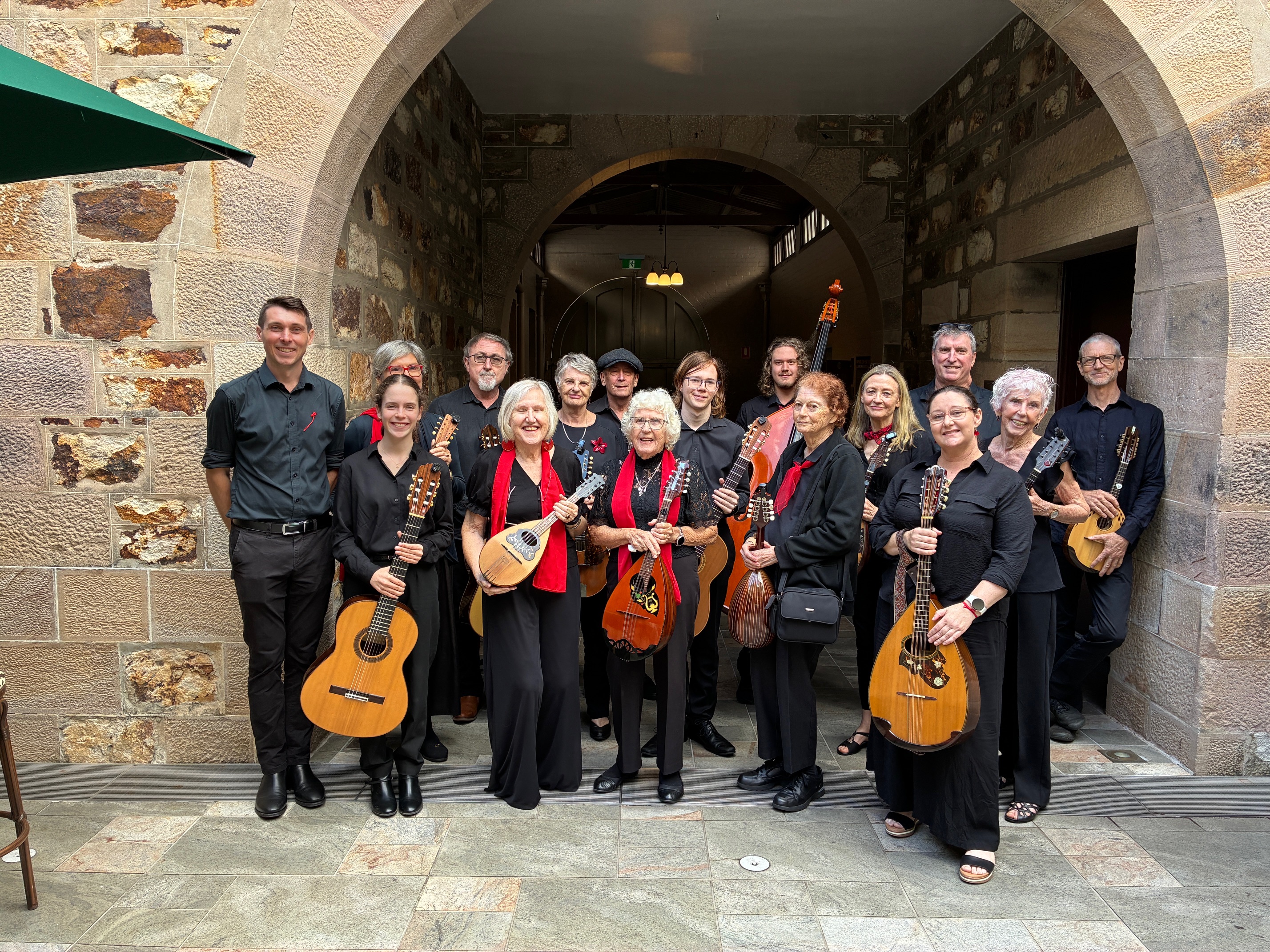 String musicians gather under a sandstone archway for a photograph 