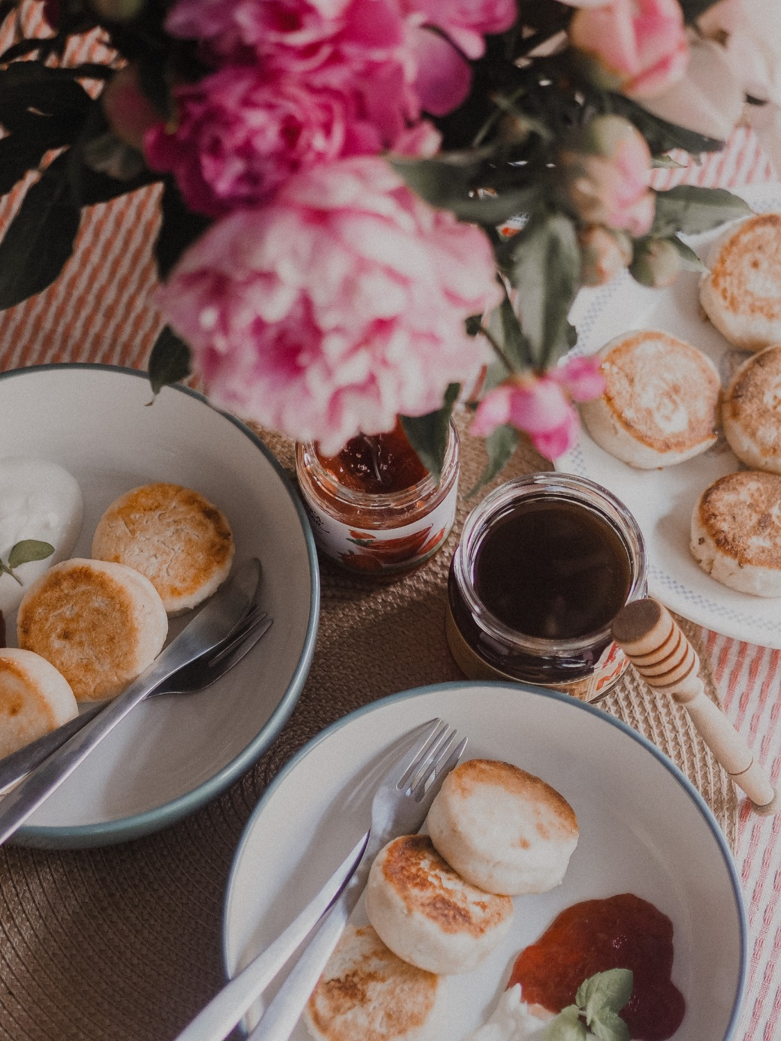 Scones, jam, cream, honey and flowers on a table