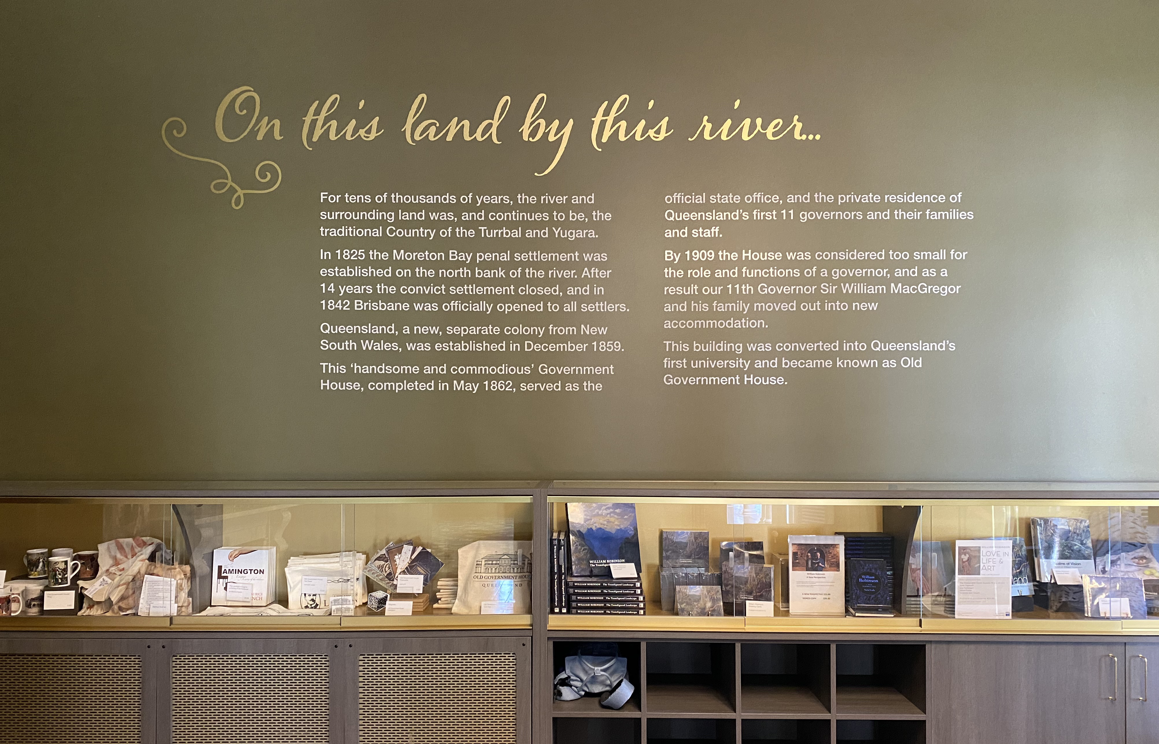 Old Government House foyer wall with text about the site and shop merchandise